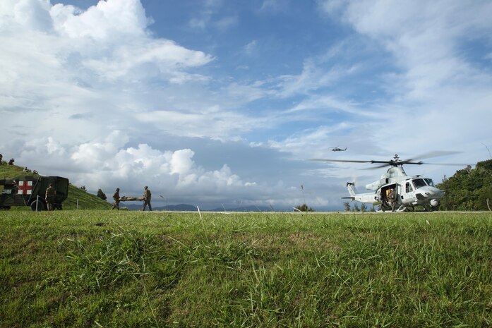 Marines with 3rd Medical Battalion, 3rd Marine Logistics Group transport a simulated casualty from a UH-1Y Venom helicopter at Landing Zone Swan on Okinawa, Japan, June 6, 2018. The simulation is part of Inochi No Onjin, an exercise utilized to validate command standard operating procedures, tactics, and techniques. The multitude of patient evacuations through the joint services increase competency of medical units' command and control abilities, medical regulating, and role-two capabilities. (U.S. Marine Corps photo by Lance Cpl. Harrison Rakhshani)