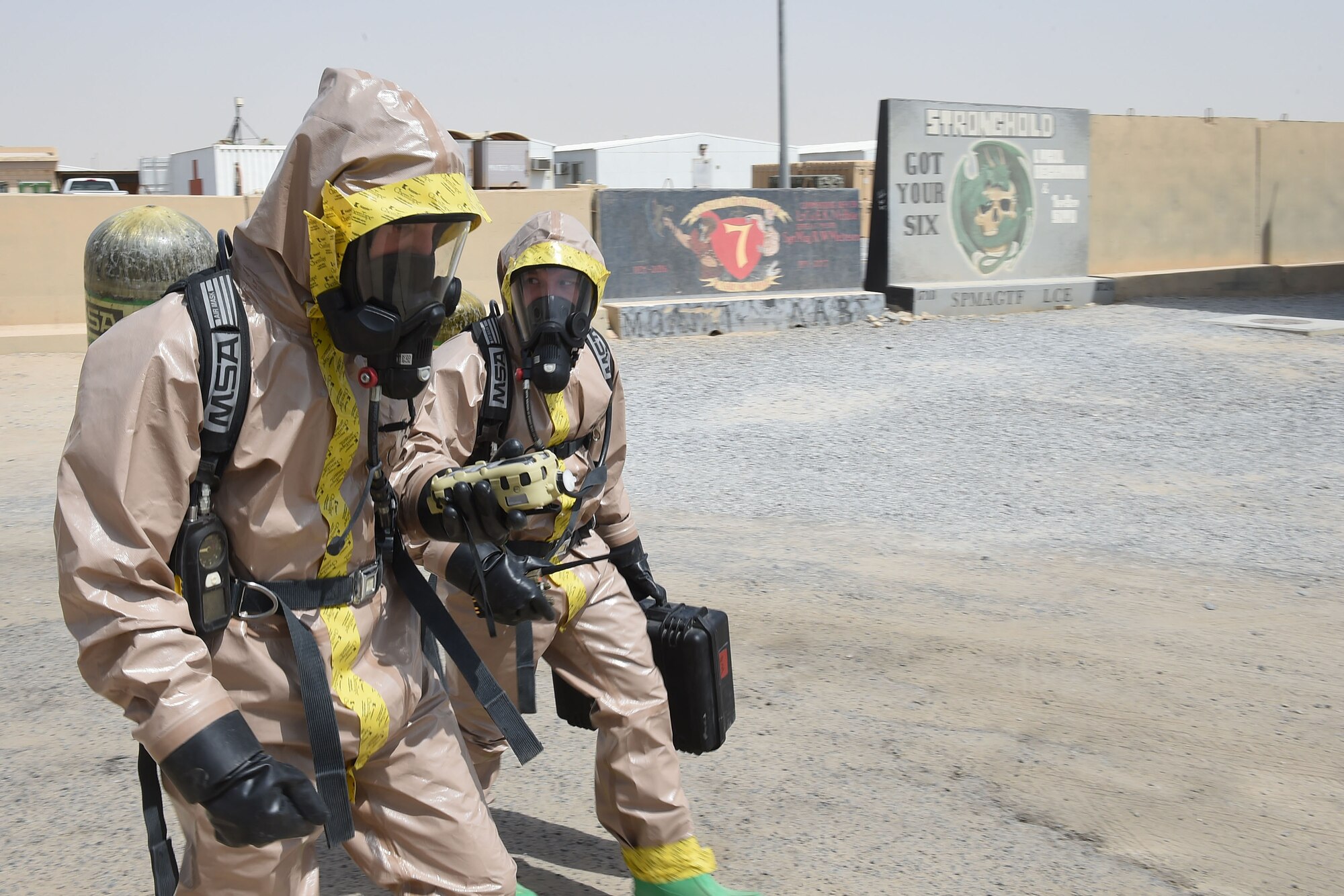 Two airmen in protective suits walk side by side