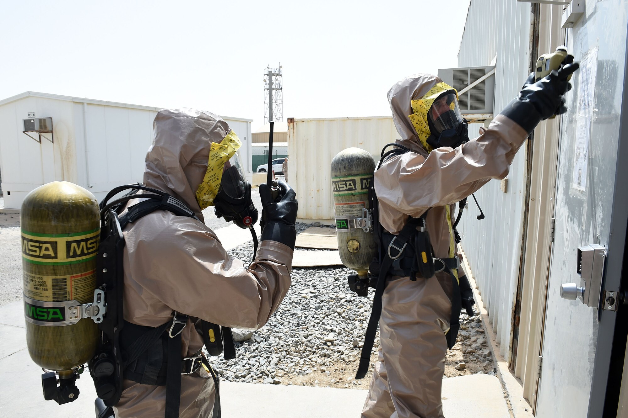 Airmen in protective suits prepare to enter building