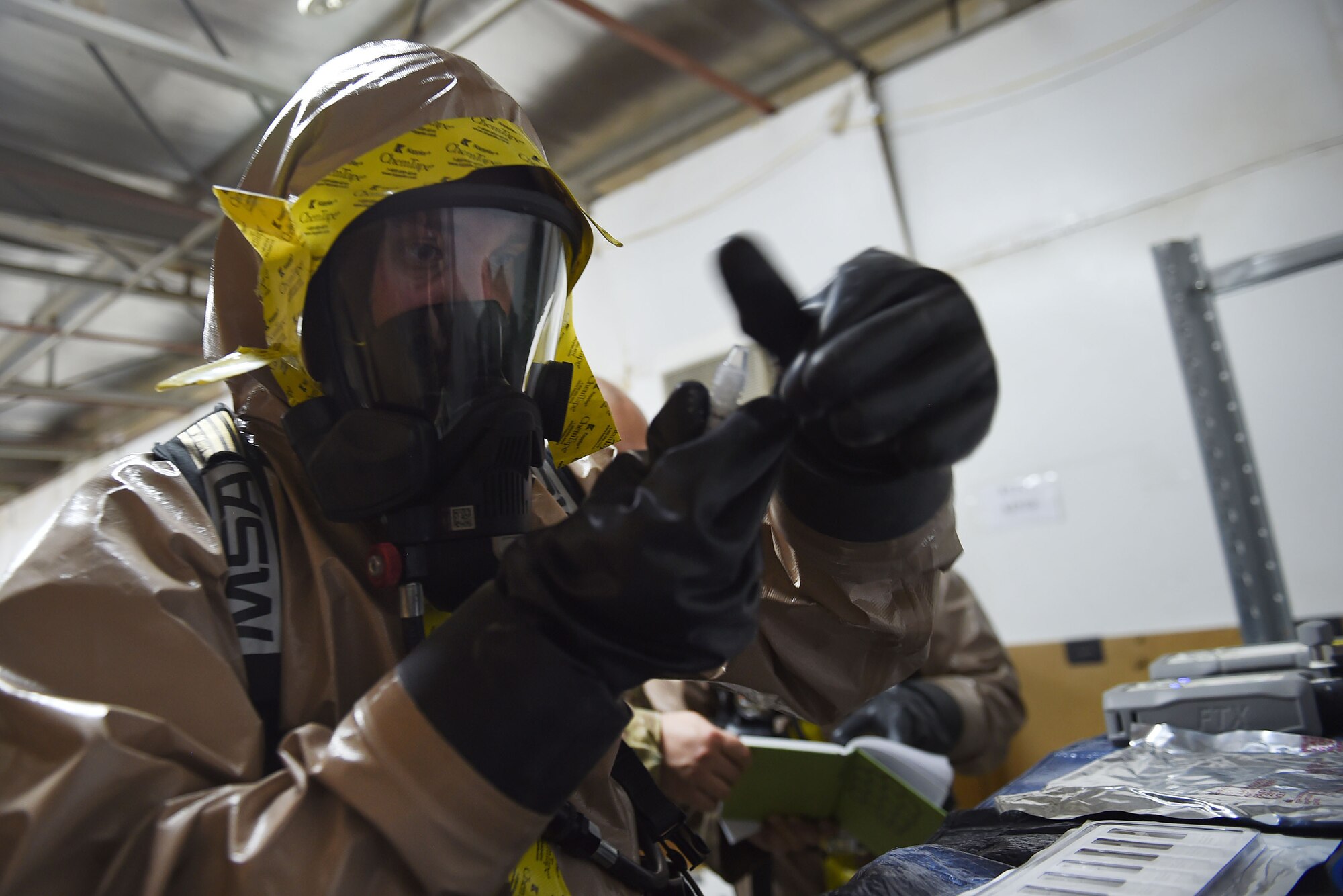Airman in a protective suit puts the cap back on a tiny bottle