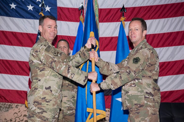 Maj. Gen. Chad Franks, 9th Air Expeditionary Task Force - Levant commander and presiding officer, gives the 332nd Air Expeditionary Wing guidon to Brig. Gen. David Iverson during a change of command ceremony, June 9, 2018, at an undisclosed location in Southwest Asia.
