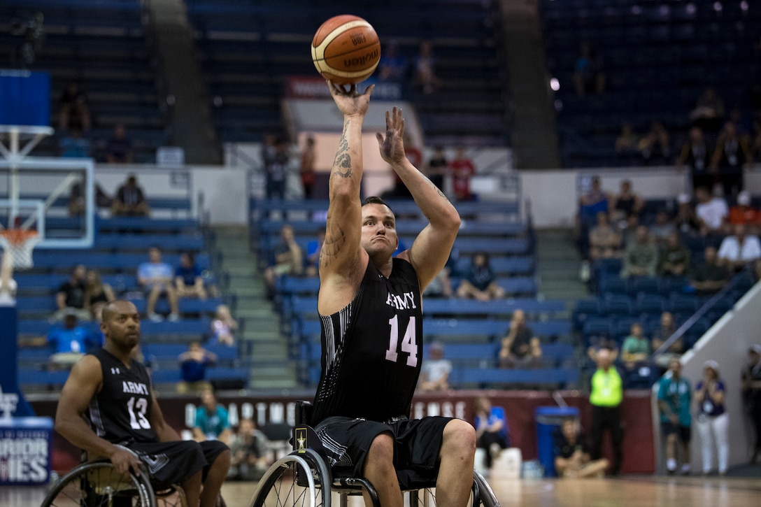 A Warrior Games athlete in a wheelchair shoots a basketball.