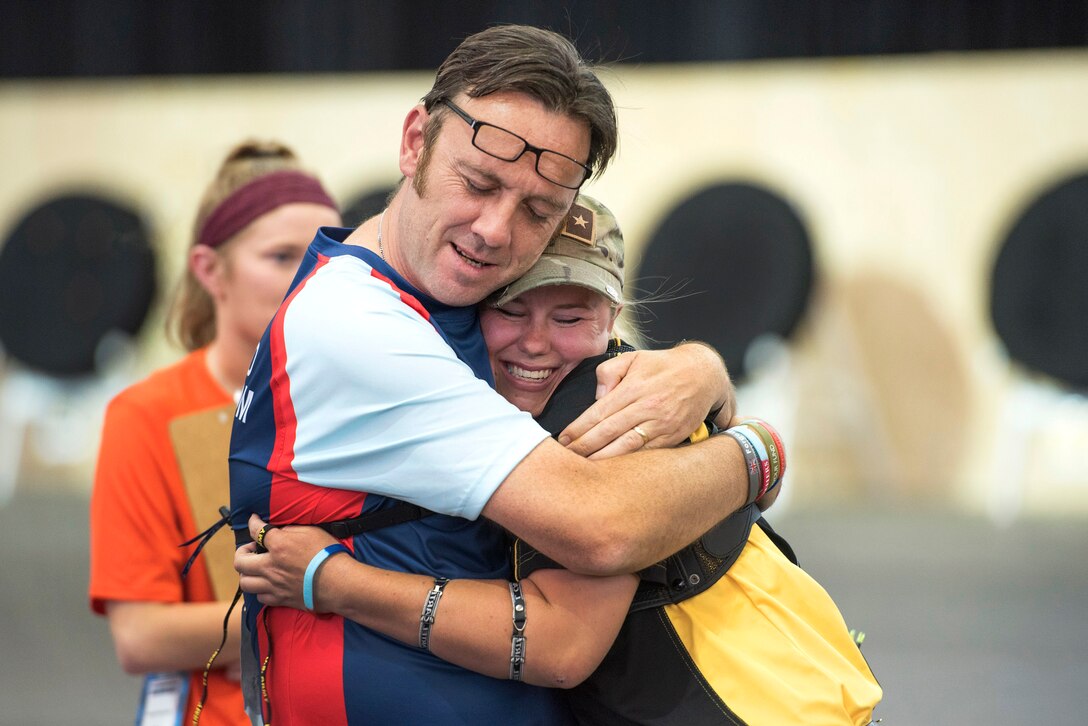 Competitors hug after competing in an archery event.