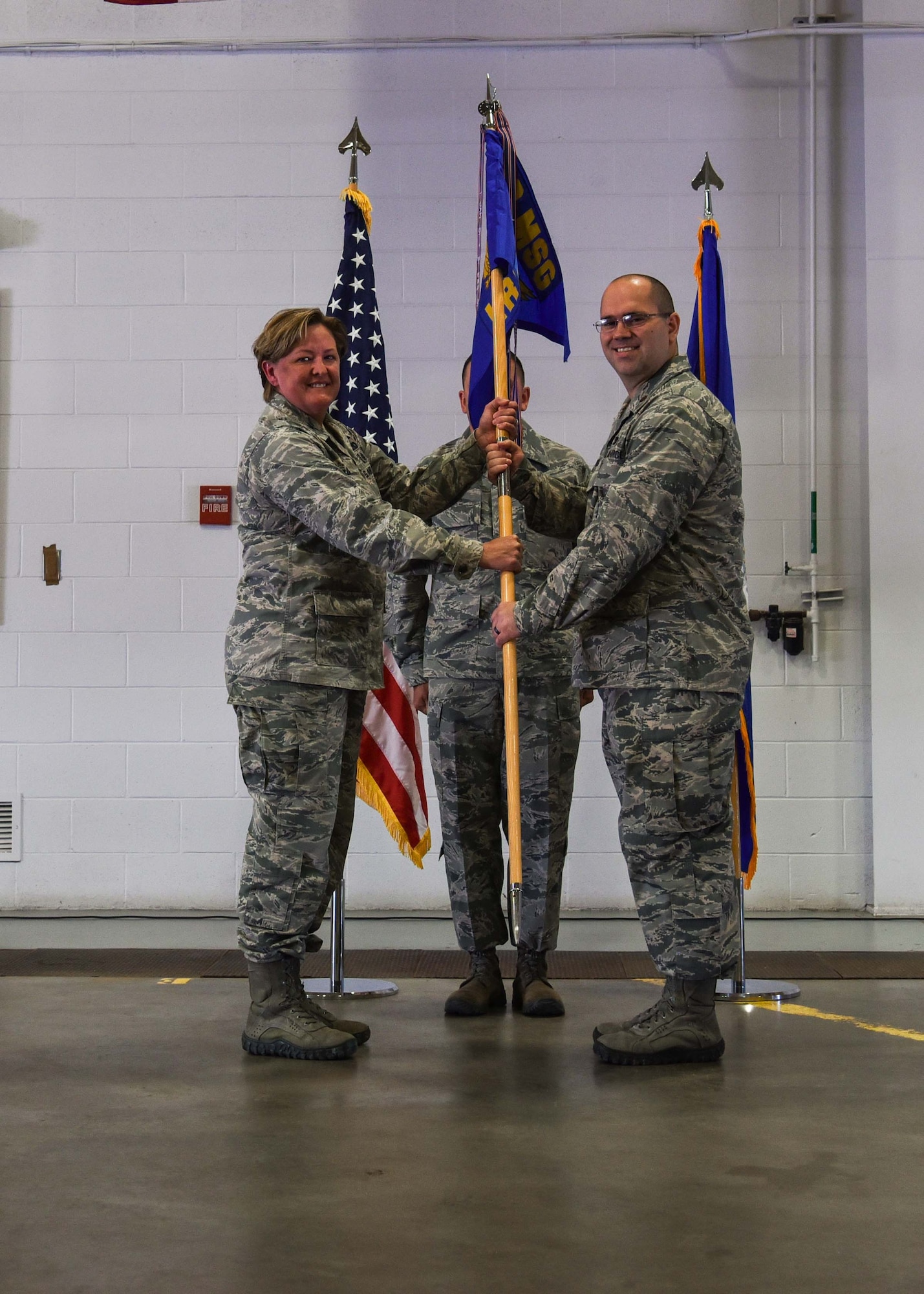 Colonel Trisha Van Den Top, 90th Mission Support Group commander, passes the 90th Logistics Readiness Squadron guidon to Maj. Joseph Montoro in the 90th LRS vehicle high bay on F.E. Warren Air Force Base, Wyo., June 6, 2018 during a change-of-command ceremony. The passing of the guidon symbolizes the authority and responsibility Montoro has as the commander of 90th LRS. (U.S. Air Force photo by Airman 1st Class Braydon Williams)