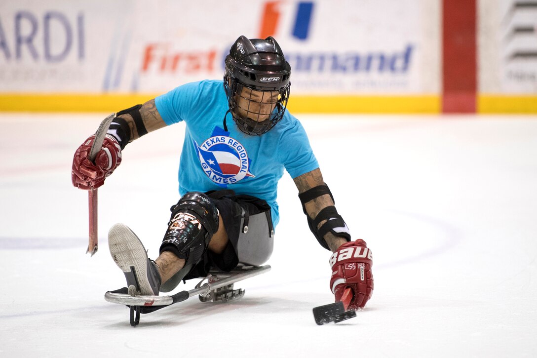 A sailor passes the puck during an exhibition sled hockey game.