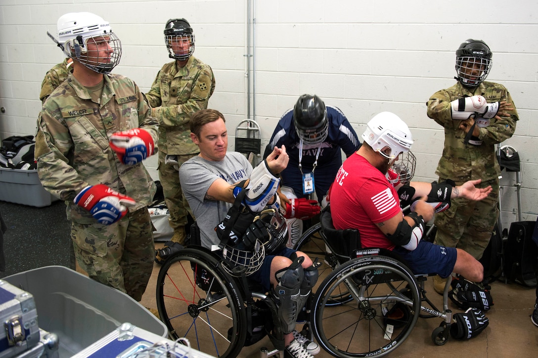 Army and sailors members suit up for an exhibition sled hockey game.