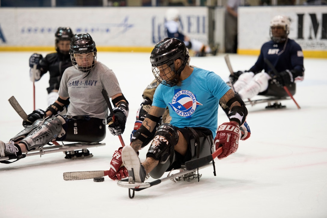 Sailors maneuver for the puck in an exhibition sled hockey game.