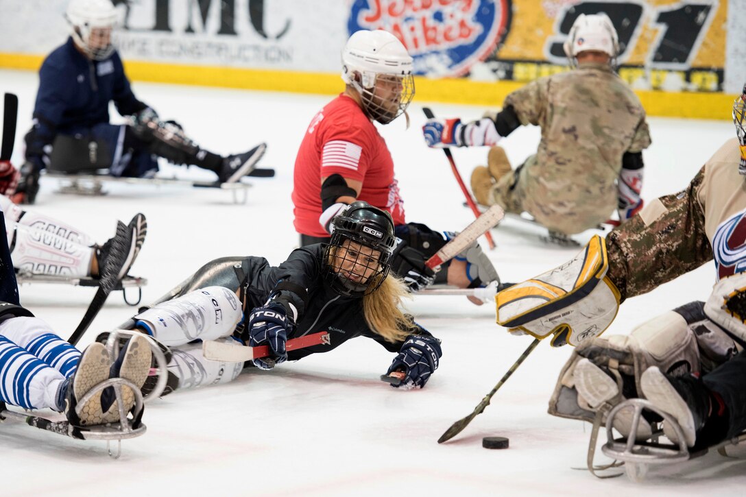 A sailor looks to score in an exhibition sled hockey game.
