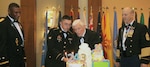 Spc. Matthew Saenz (second from left), a supply clerk with U.S. Army South, joins retired Army Brig. Gen. Charles V.L. Elia in the ceremonial cake cutting at San Antonio’s 243rd U.S. Army Birthday Celebration at the Grand Hyatt Riverwalk Hotel June 9.  Saenz, 20, and Elia, 97, were the youngest and oldest Soldiers present and had the privilege of slicing the first piece of cake.  Maj. Gen. Patrick Sargent (far left), U.S. Army Medical Department Center & School commanding general, observes the long-standing tradition with Command Sgt. Maj. William O’Neal (far right), AMEDDC&S senior enlisted advisor.