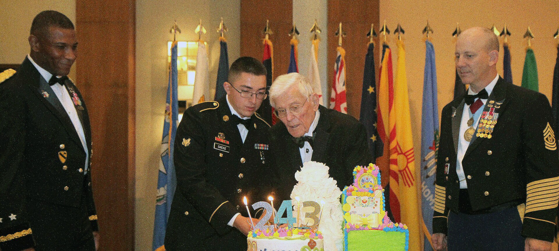 Spc. Matthew Saenz (second from left), a supply clerk with U.S. Army South, joins retired Army Brig. Gen. Charles V.L. Elia in the ceremonial cake cutting at San Antonio’s 243rd U.S. Army Birthday Celebration at the Grand Hyatt Riverwalk Hotel June 9.  Saenz, 20, and Elia, 97, were the youngest and oldest Soldiers present and had the privilege of slicing the first piece of cake.  Maj. Gen. Patrick Sargent (far left), U.S. Army Medical Department Center & School commanding general, observes the long-standing tradition with Command Sgt. Maj. William O’Neal (far right), AMEDDC&S senior enlisted advisor.