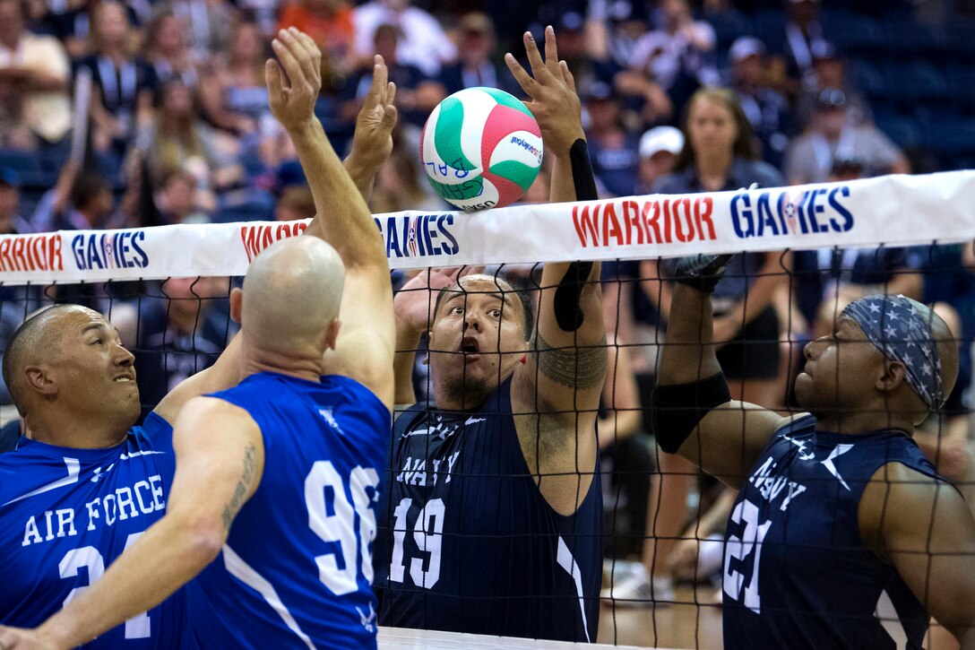A sailor blocks a shot at the net during the sitting volleyball gold medal round.