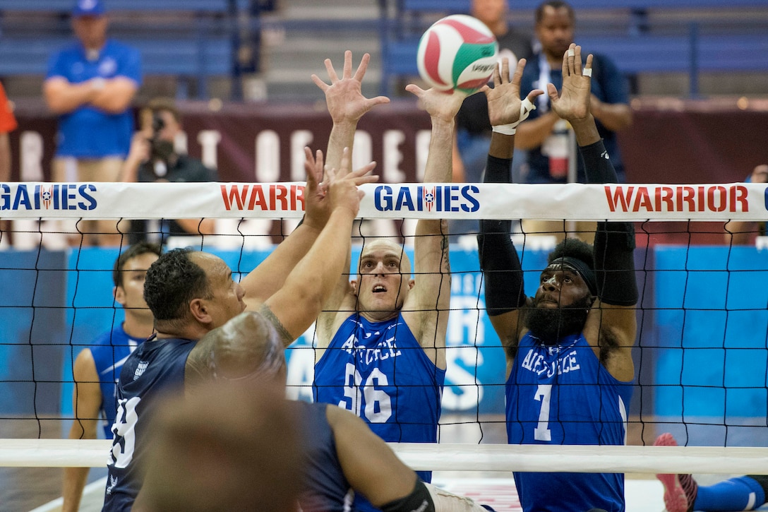 A sailor tries to tip the ball past an airmen.