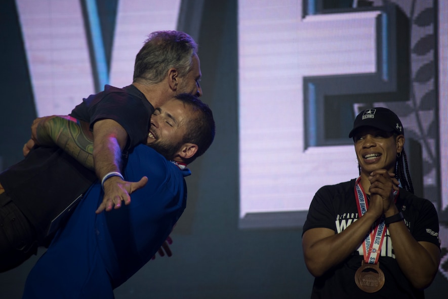 Rafael Morfinenciso, Department of Defense Warrior Games athlete and Team Air Force member, embraces Jon Stewart, television personality and event host, after winning the "ultimate champion" silver medal during the closing ceremony of the Games held at the U.S. Air Force Academy, Colorado Springs, Colo., June 9, 2018. To earn the ultimate champion title, athletes had to compete in their respective functional classifications in eight sporting events, earning points for each of their performances. The athletes with the highest cumulative points after their eight events won the bronze, silver and gold ultimate champion medals. (U.S. Air Force photo by Senior Airman Dennis Hoffman)