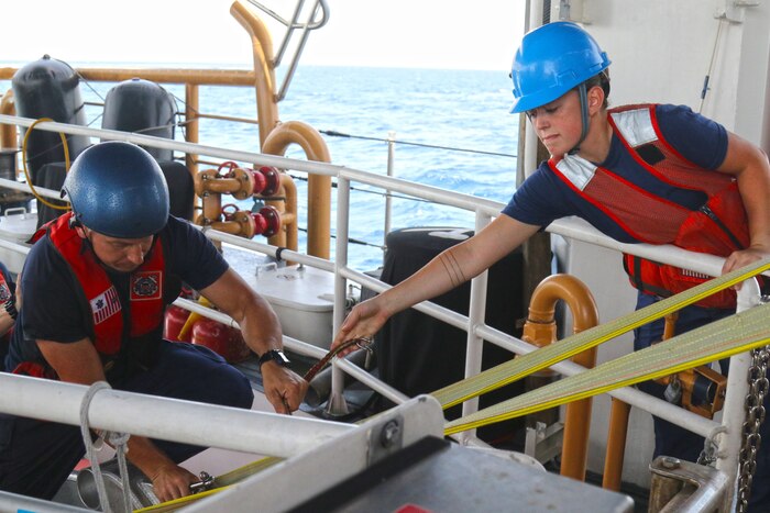 Two members of the Coast Guard work on a ship.