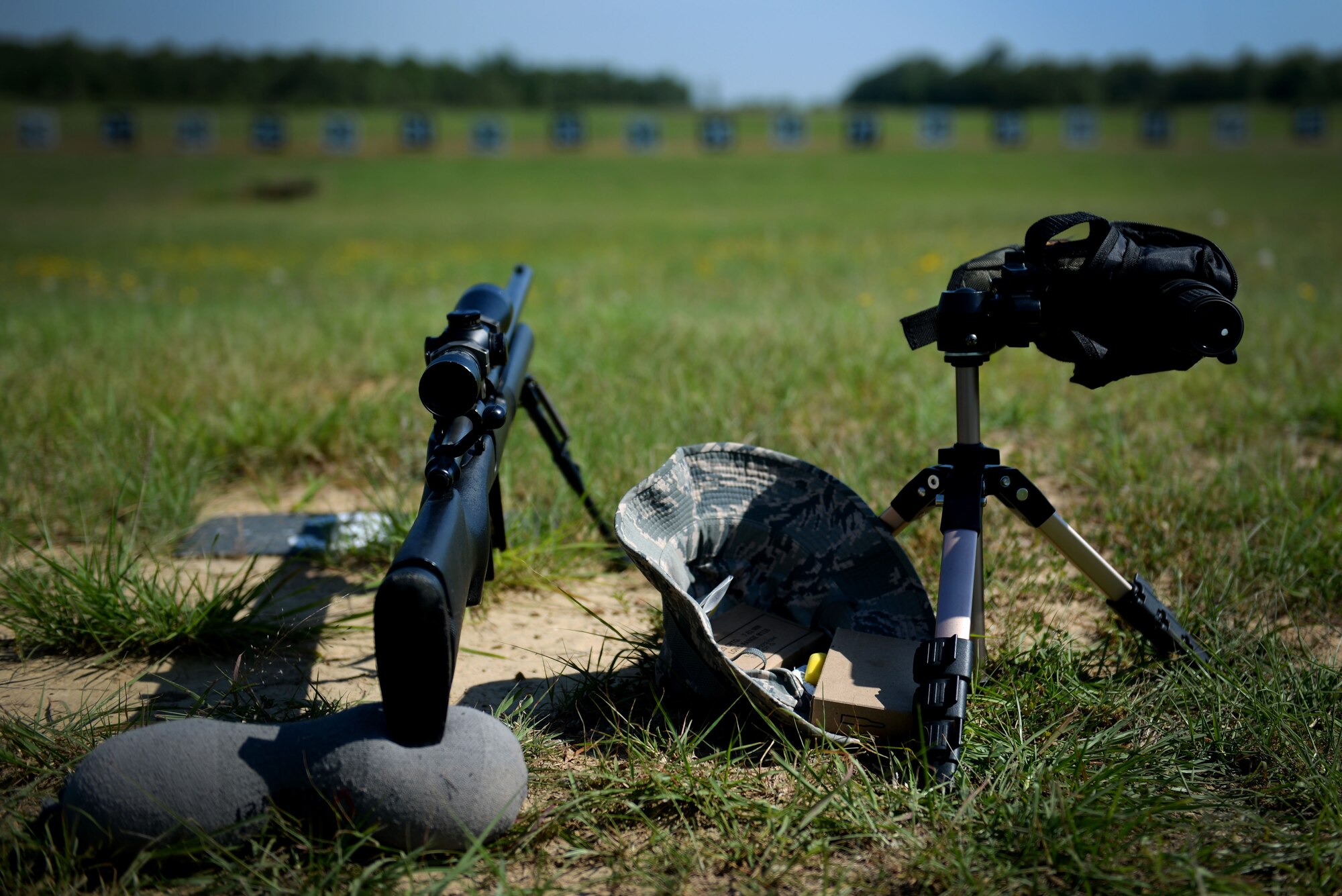 An M24 sniper weapon system, scope and hat lay on the ground.