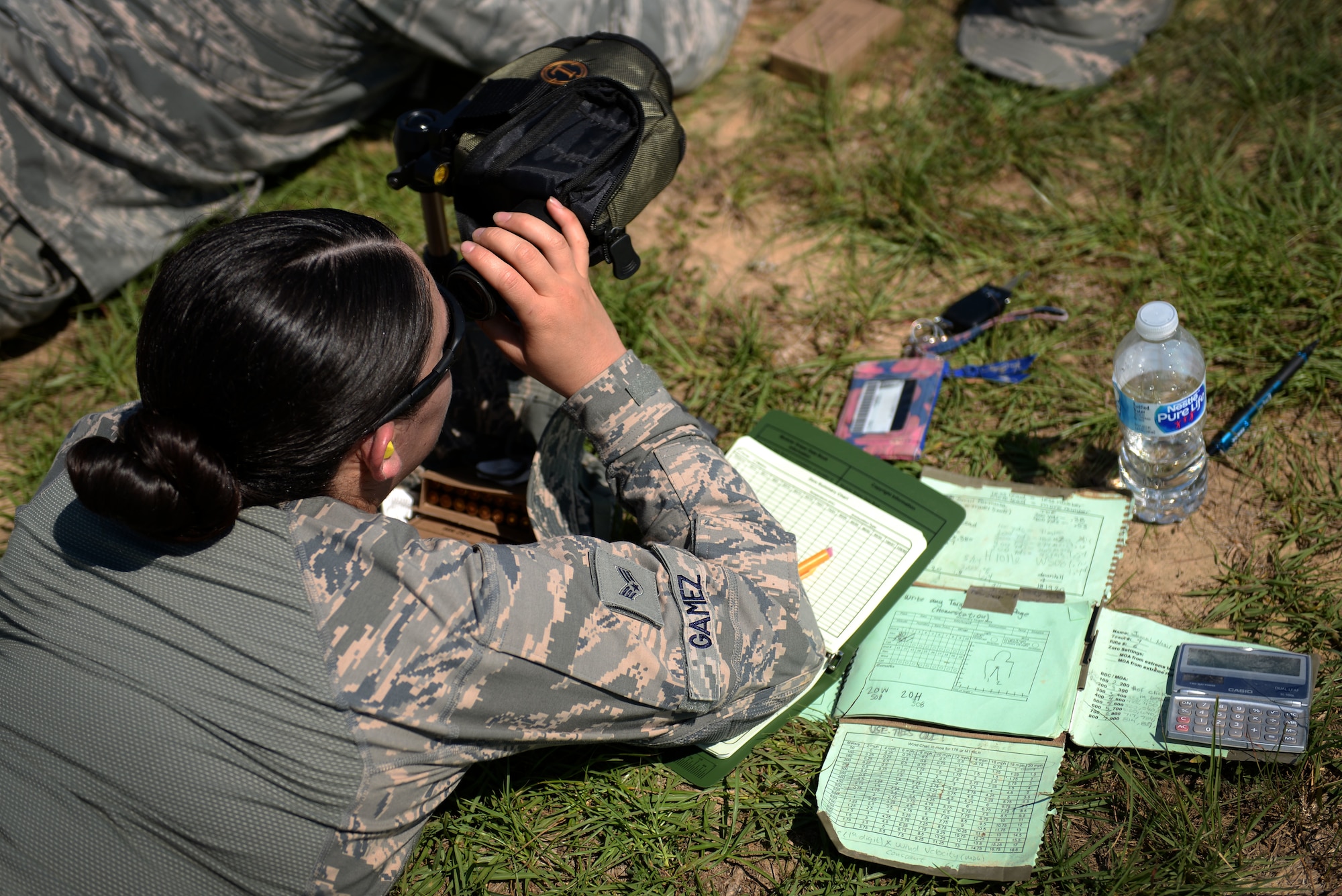 Woman in the Airman Battle Uniform looks through a scope.