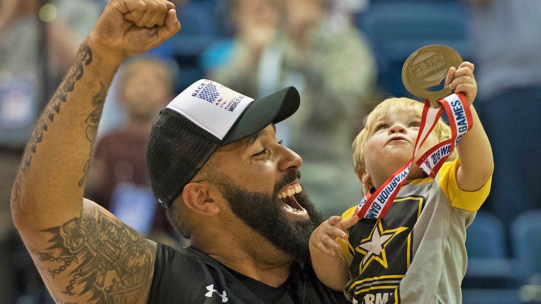 Army Sgt. Chris McGinnis and his 17-month-old son Ace celebrate Army's gold medal in wheelchair basketball.