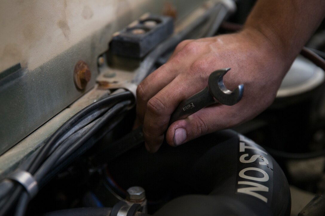 Lance Cpl. Michael Ramirez, a motor transport mechanic with Battalion Landing Team, 1st Battalion, 1st Marines, tightens the bolts on a vehicle engine during a maintenance stand-down at Camp Hansen, Okinawa, Japan, May 9, 2018.