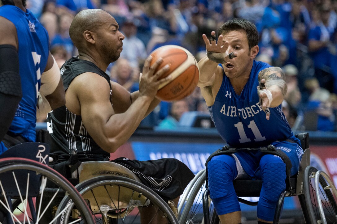 Army Spc. Brent Garlic battles Air Force Master Sgt. Kenneth Guinn for the ball as Army defeats Air Force to win gold in wheelchair basketball.
