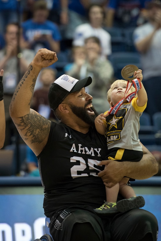 Army Sgt. Chris McGinnis and his 17-month-old son Ace celebrate Army's gold medal in wheelchair basketball.