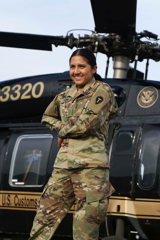 Pilot poses in front of helicopter.