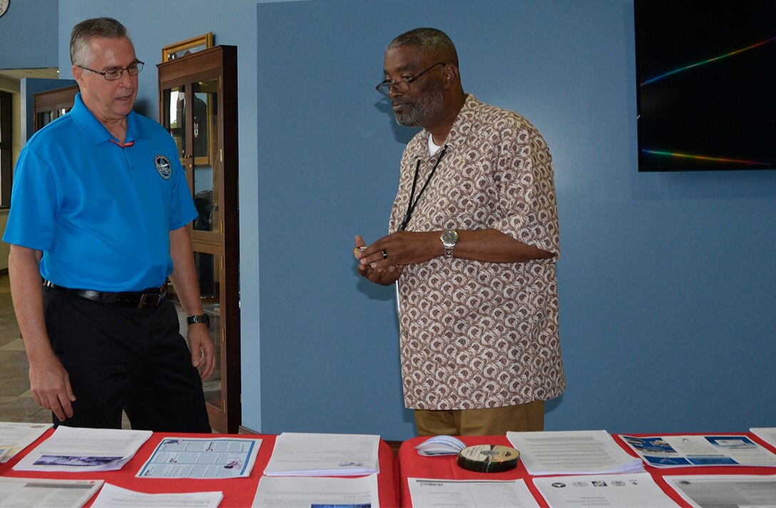 John Bender, 1st Air Force (Air Forces Northern) Installation and Mission Support Directorate, talks with Don Howell, 1st AF (AFNORTH) Manpower, Personnel and Services Directorate, about some of the hurricane preparedness materials he’s available on a table in the Killey Center for Homeland Operations here June 12. The 2018 hurricane season started June 1 during which  meteorology officials estimate there will be 14 named storms with seven becoming full-up hurricanes. (Photo by Mary McHale)