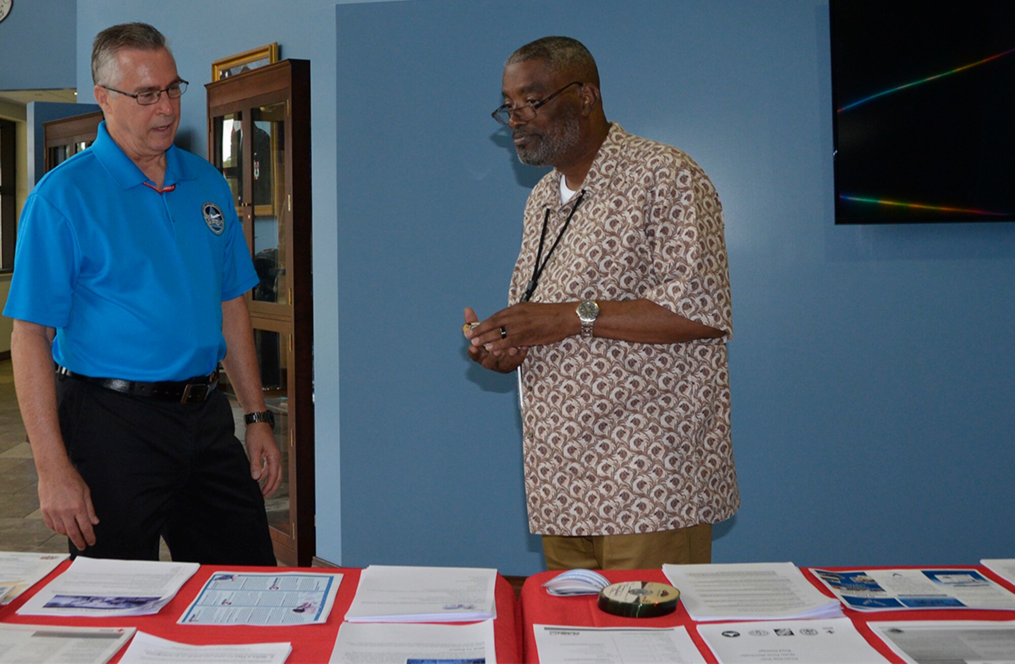John Bender, 1st Air Force (Air Forces Northern) Installation and Mission Support Directorate, talks with Don Howell, 1st AF (AFNORTH) Manpower, Personnel and Services Directorate, about some of the hurricane preparedness materials he has available on a table in the Killey Center for Homeland Operations here June 12. The 2018 hurricane season started June 1 during which  meteorology officials estimate there will be 14 named storms with seven becoming full-up hurricanes. (Photo by Mary McHale)