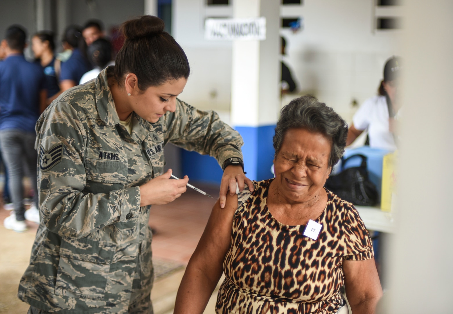 An Air Force medic gives a woman a shot.