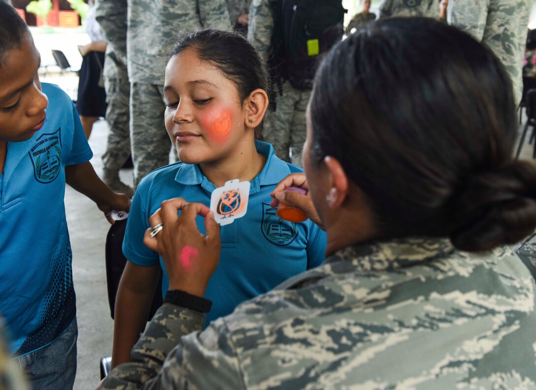A U.S. Air Force member paints the face of a girl.