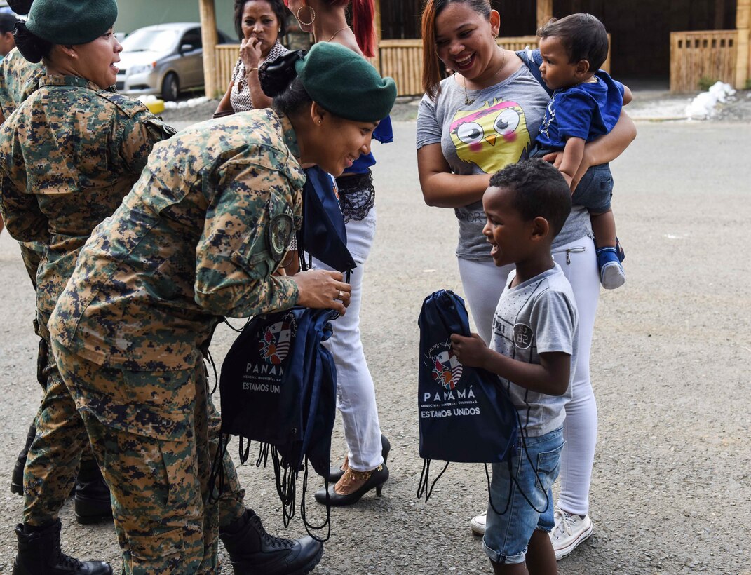 A Panama official passes bags out to children.