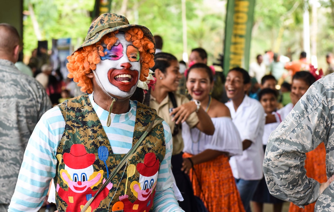 A clown leads a line of guests through a crowd.