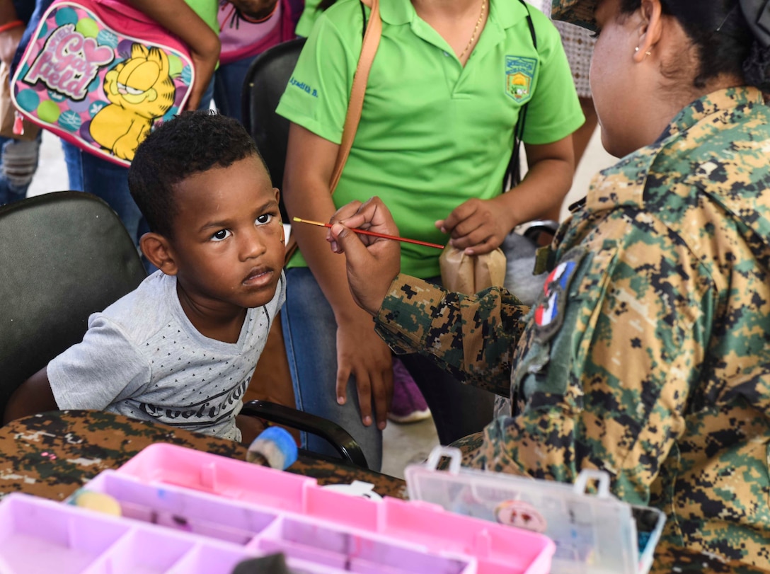 A uniformed official paints the face of a child