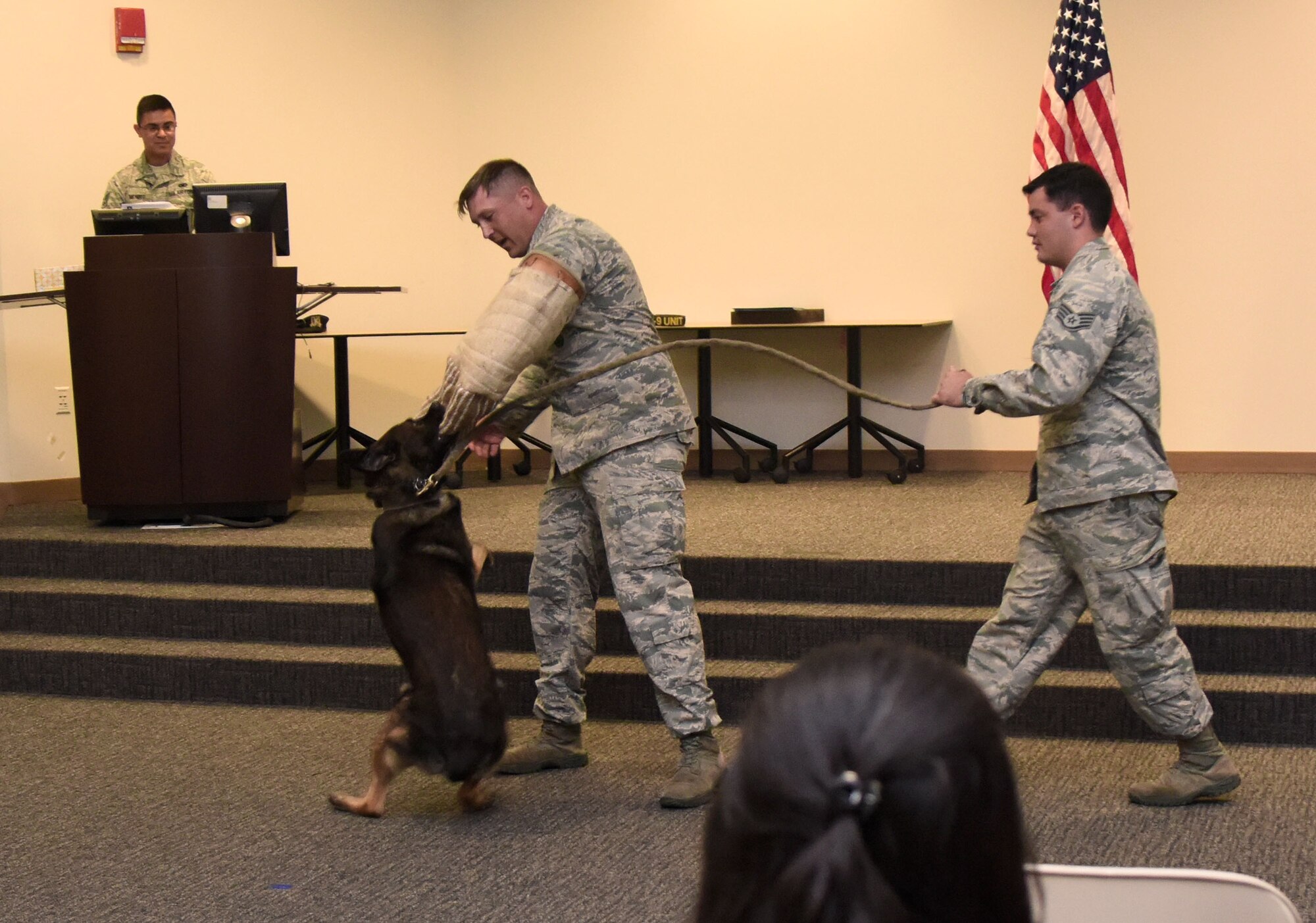 U.S. Air Force Staff Sgts. William Herron and Matthew Ratchford, 81st Security Forces Squadron military working dog handlers, and Toki, 81st SFS MWD, participate in a ceremonial final bite during a retirement ceremony at the Roberts Consolidated Aircraft Maintenance Facility at Keesler Air Force Base, Mississippi, June 8, 2018. Toki retired with over 10 years of military service and following his retirement Ratchford will be adopting him. (U.S. Air Force photo by Kemberly Groue)