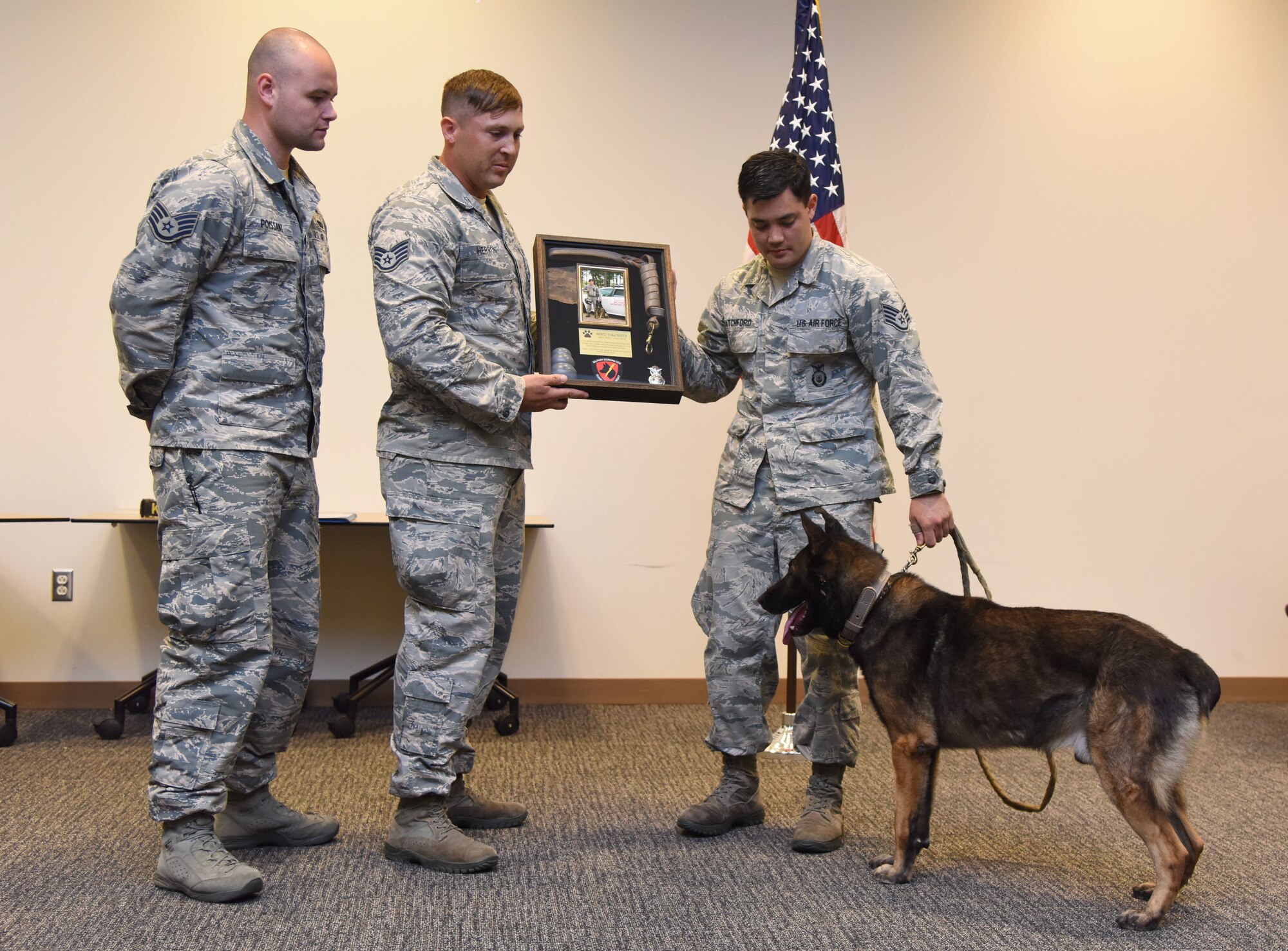 Members from the 81st Security Forces Squadron present a shadowbox to U.S. Air Force Staff Sgt. Matthew Ratchford, 81st Security Forces Squadron military working dog handler, for Toki, 81st SFS MWD, during a retirement ceremony at the Roberts Consolidated Aircraft Maintenance Facility at Keesler Air Force Base, Mississippi, June 8, 2018. Toki served one of four deployments with Ratchford. (U.S. Air Force photo by Kemberly Groue)