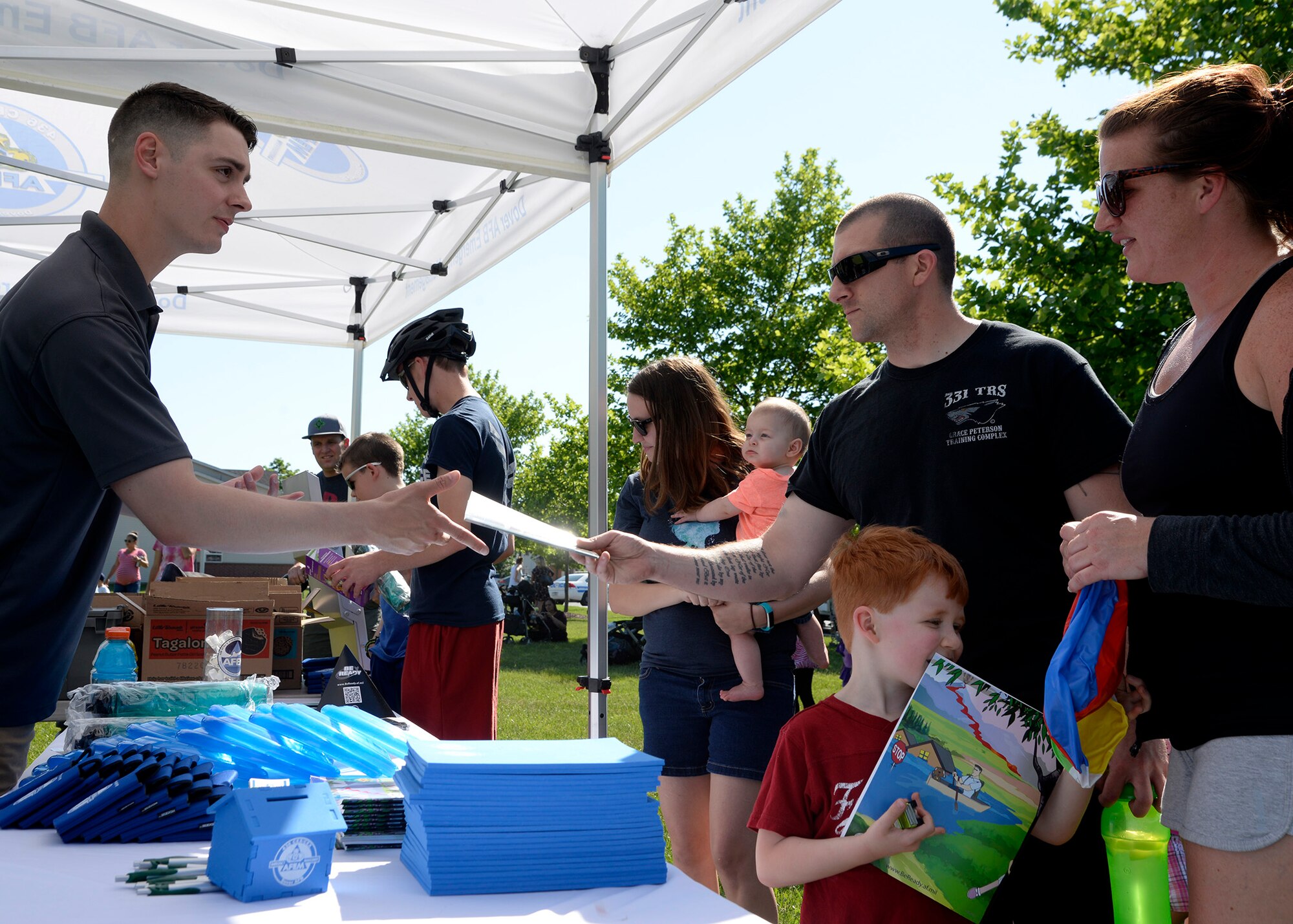 Senior Airman James Perry, 436th Civil Engineer Squadron emergency management apprentice, distributes disaster preparedness items to families May 24, 2018, during a hurricane block party in base housing on Dover Air Force Base, Del. The event was held to inform base residents on the hazards of being stationed on the coast during storm season. (U.S. Air Force photo/Tech. Sgt. Matt Davis)