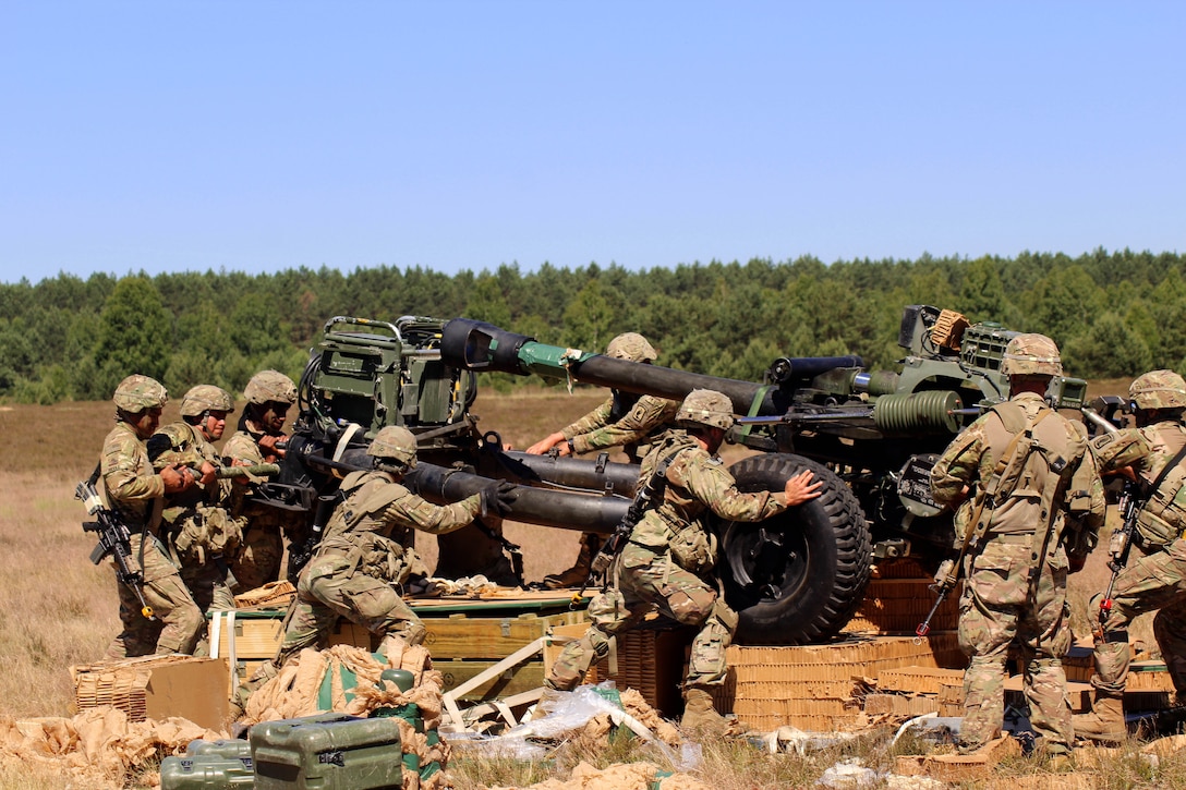 Soldiers reassemble a M119 105 mm howitzer and position it for a fire mission.