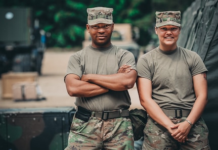 Pfc. Roffes Watson and Pfc. Renee Shaw stand next the the field showers at their forward operating base during Saber Strike 18, June 1, 2018. Pfc. Watson and Pfc. Shaw will be performing field shower and laundry support with the 464th Quartermaster Company during Saber Strike 18.