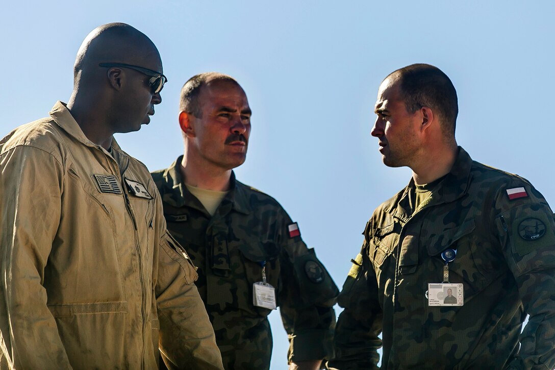 A Marine discusses M1A1 Abrams tank capabilities with Polish air force members.