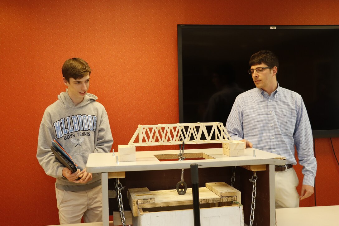 High School Intern Josh Dalton and Structural Engineer and High School Intern Program Coordinator Nathan Fox, prepare for the bridge break that will determine the weight-bearing capability of his design.