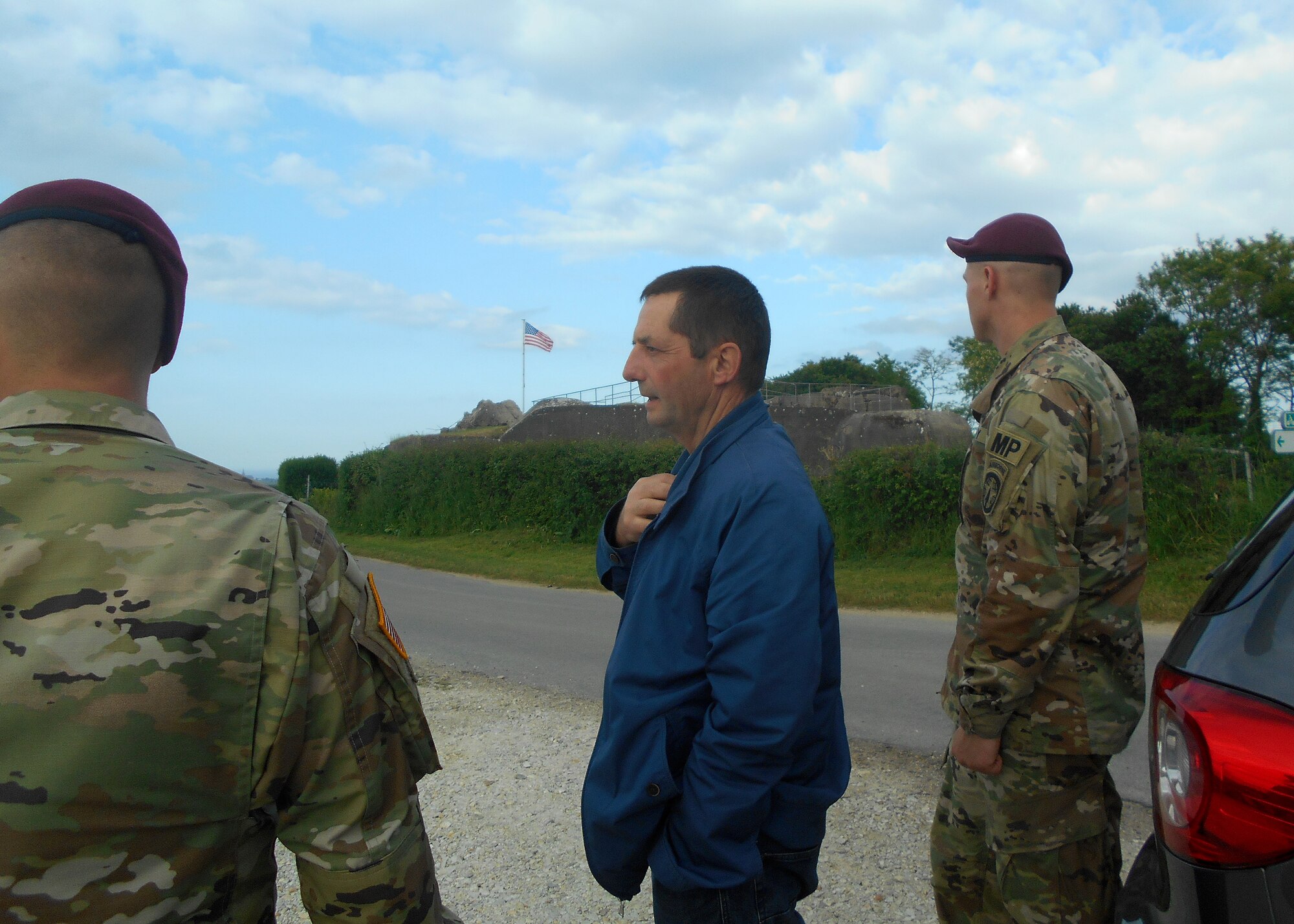 Service members speak to a Normandy local outside.