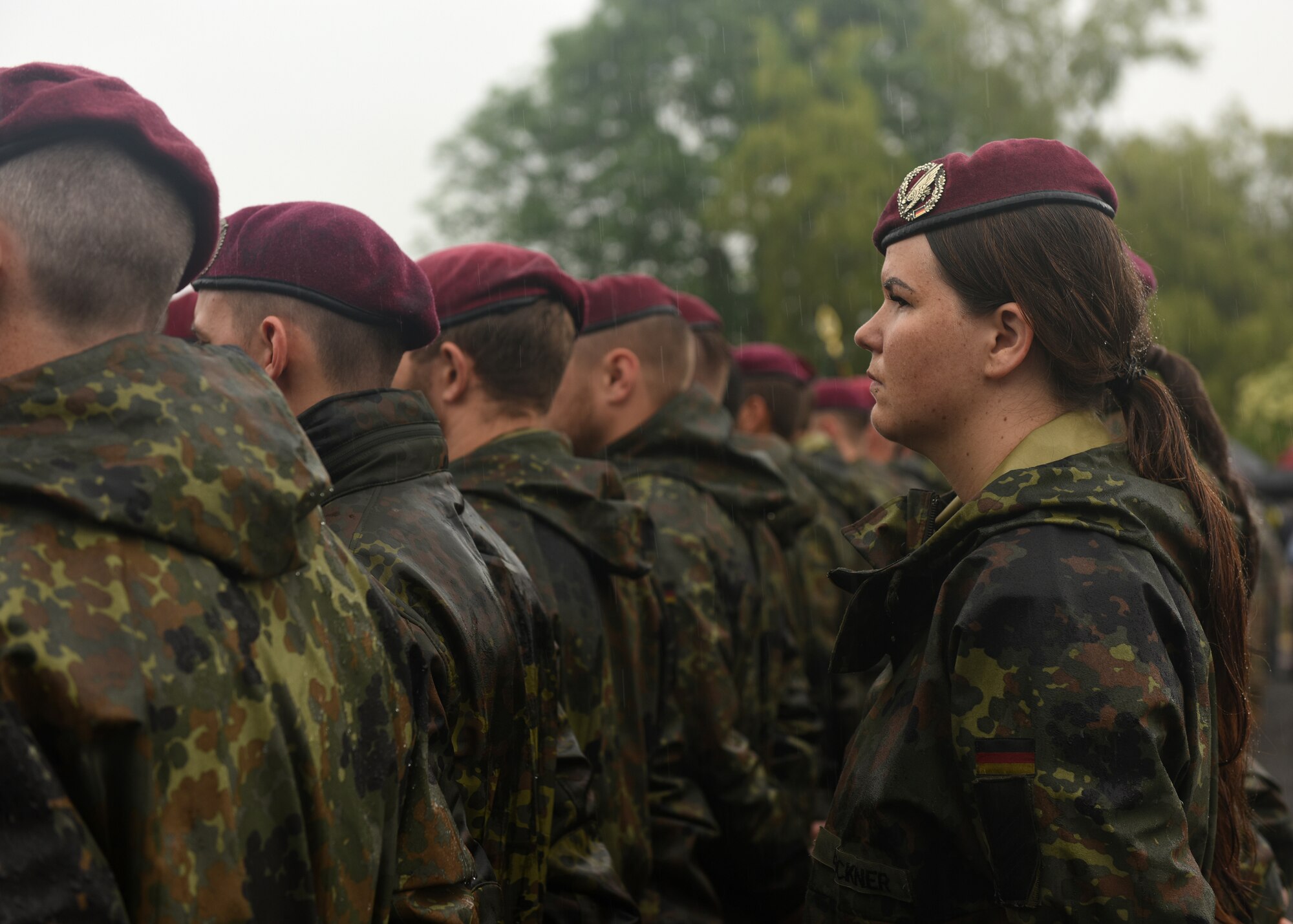 Service members observe a ceremony in the rain.