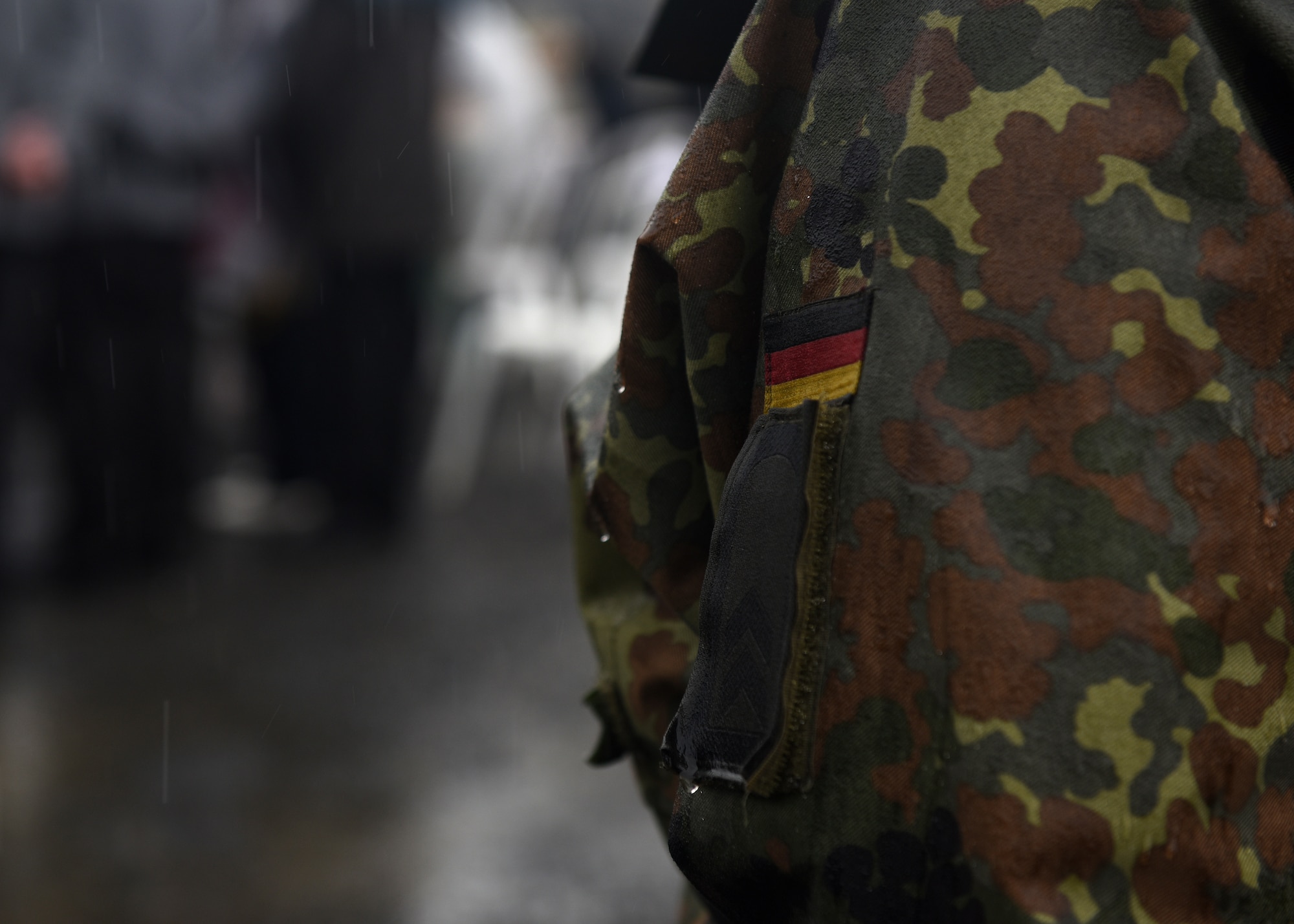 Service members observe a ceremony in the rain.