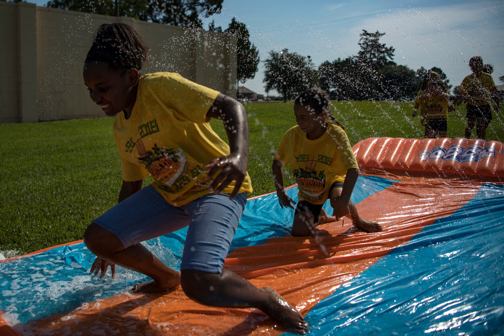 Children slide across a water slide during the base chapel’s Vacation Bible School, June 8, 2018, at Moody Air Force Base, Ga. VBS is designed to assist children in building resiliency to the stressors many military families face. More than 95 children and 65 volunteers attended this year’s VBS. (U.S. Air Force photo by Senior Airman Daniel Snider)
