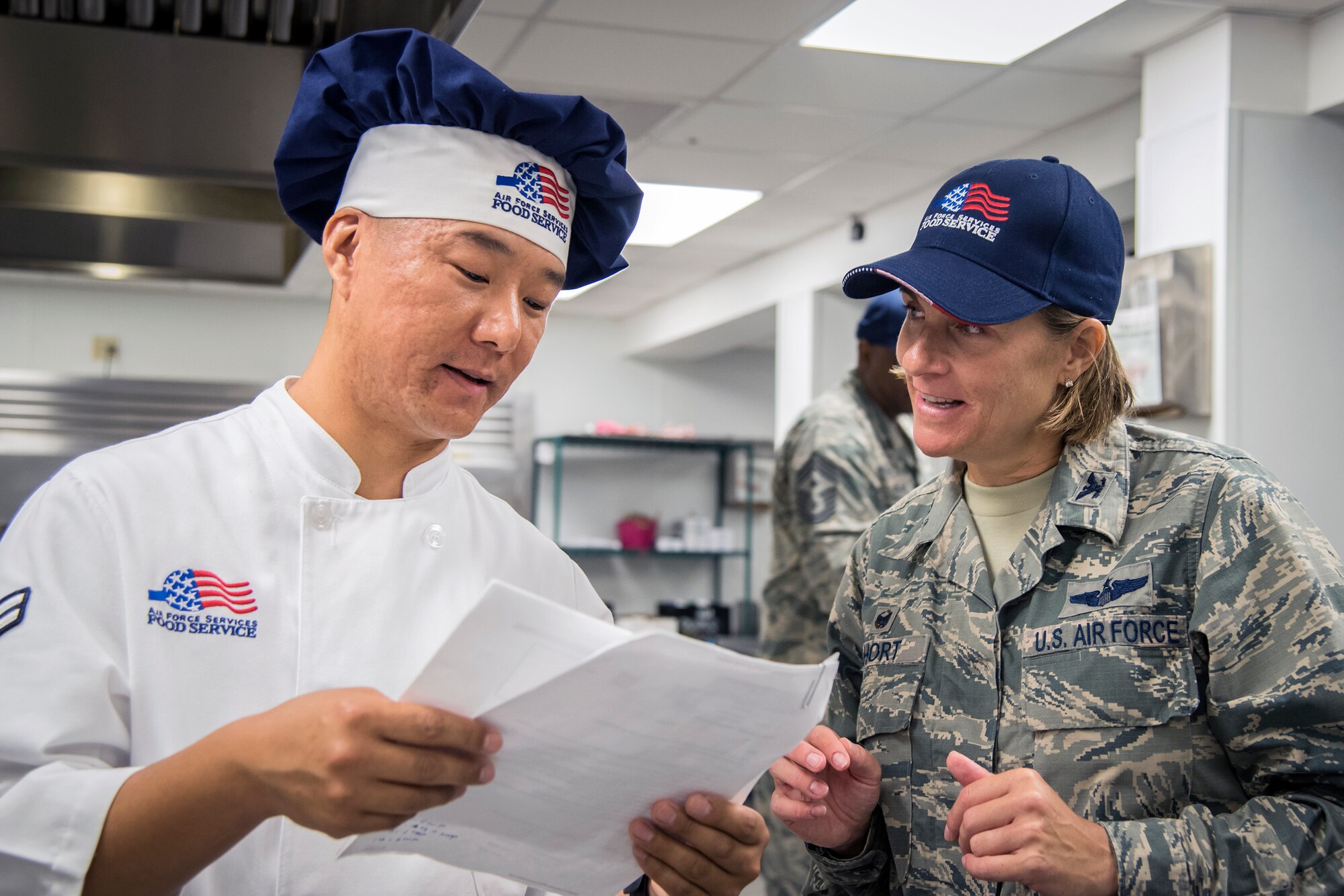 Airman 1st Class Pema Sherpa, left, 23d Force Support Squadron services journeyman, teaches a recipe to Col. Jennifer Short, 23d Wing (WG) commander, during an immersion tour, June 11, 2018, at Moody Air Force Base, Ga. Short and Chief Master Sgt James Allen, 23d WG command chief, toured the Georgia Pines Dining Facility and the Information Learning Center to gain a better understanding of their overall mission, capabilities and comprehensive duties. 	(U.S. Air Force photo by Airman 1st Class Eugene Oliver)