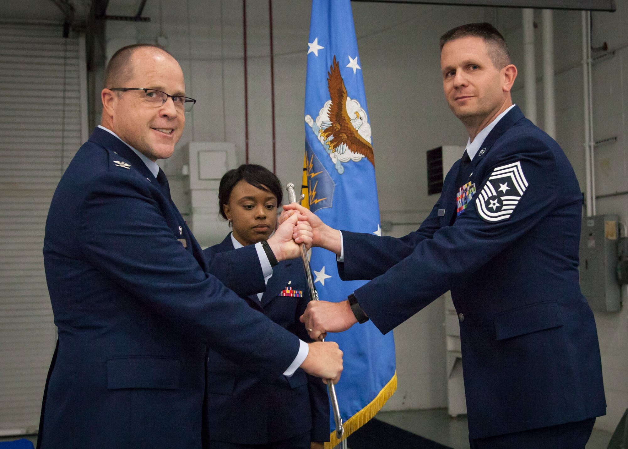 U.S. Air Force Col. James Locke, wing commander of the 128th Air Refueling Wing, hands the Chief’s Saber to Command Chief Master Sgt. Thomas Fredrickson during a change of authority ceremony Oct. 14, 2017.