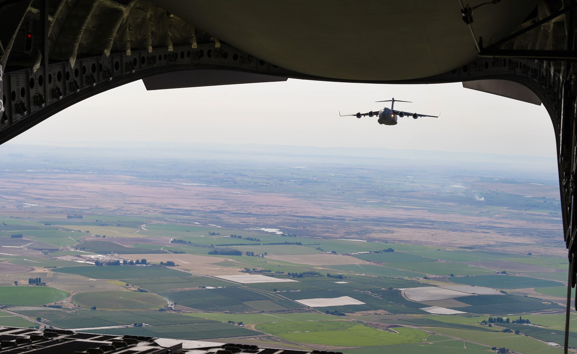 A C-17 Globemaster III flies behind another C-17 during Exercise Rainier War near Moses Lake, Wash., June 6, 2018. During the exercise, 20 C-17s from the U.S. and Australia performed actual container delivery system (CDS) and heavy equipment airdrops at the Rainier Drop Zone near Moses Lake, and simulated improved CDS, CDS and high altitude low opening personnel airdrops throughout the western United States. (U.S. Air Force photo by Senior Airman Tryphena Mayhugh)