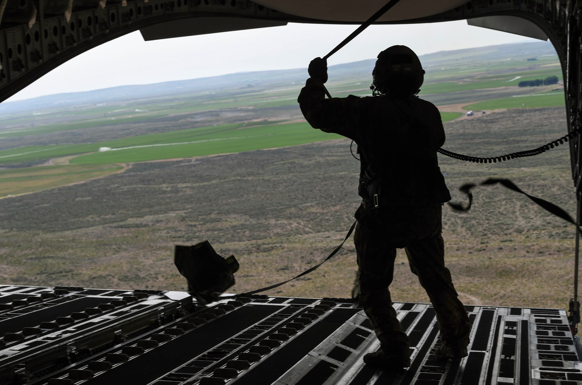 Airman 1st Class Samantha Martino, 7th Airlift Squadron loadmaster, reels in parachute covers after dropping two bundles from a C-17 Globemaster III during Exercise Rainier War at the Rainier Drop Zone near Moses Lake, Wash., June 6, 2018.  The purpose of exercise was to highlight the C-17’s capabilities to perform the Air Force’s core competencies of rapid global mobility and precision engagement. (U.S. Air Force photo by Senior Airman Tryphena Mayhugh)