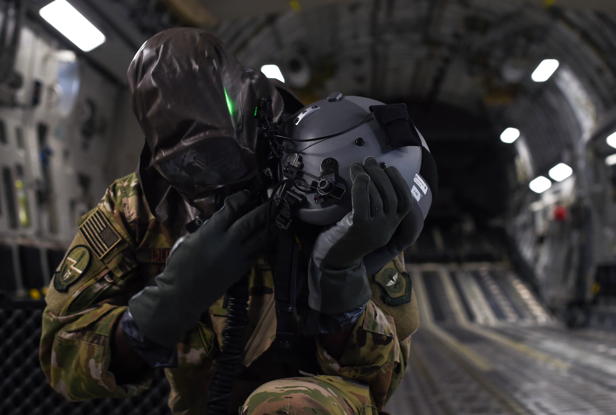 First Lt. Edmund Duvall, 7th Airlift Squadron pilot, removes an aircrew eye and respiratory protection system (AERPS) while flying in a C-17 Globemaster III during Exercise Rainier War near Moses Lake, Wash., June 6, 2018. The crew’s ability to put on AERPS gear properly was one aspect they trained on during the exercise. (U.S. Air Force photo by Senior Airman Tryphena Mayhugh)