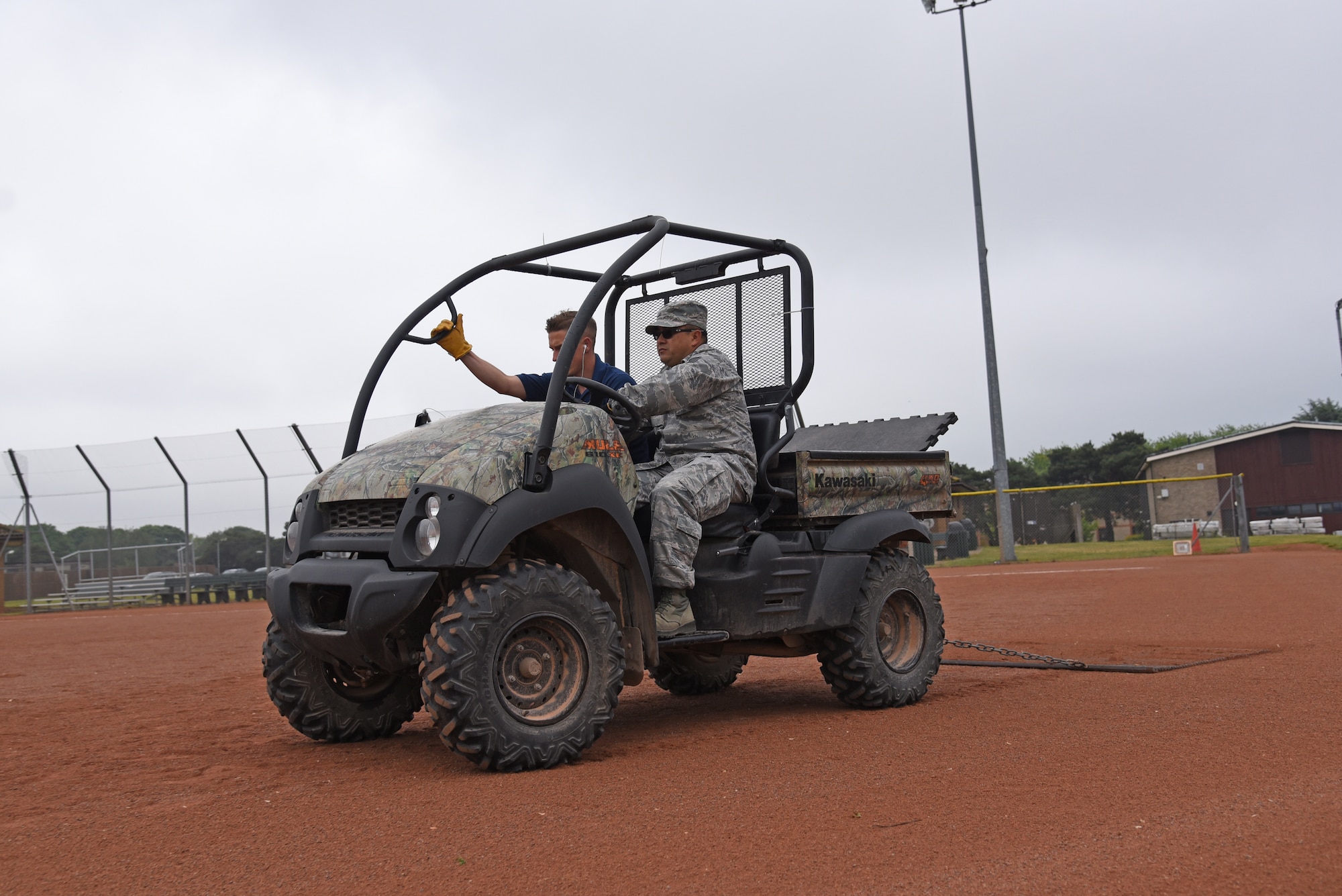 An Airman from the 161st Force Support Squadron, accompannied by his counterpart from the 48th Force Support Squadron, uses a utility vehicle to groom a softball field before an upcoming tournament at Royal Air Force Lakenheath, England May 30, 2018. The Airman worked with multiple section of the 48th FSS to get a variety of valuable training and experience to help improve knowledge and mission readiness. (U.S. Air National Guard photo by Staff Sgt. Dillon Davis)