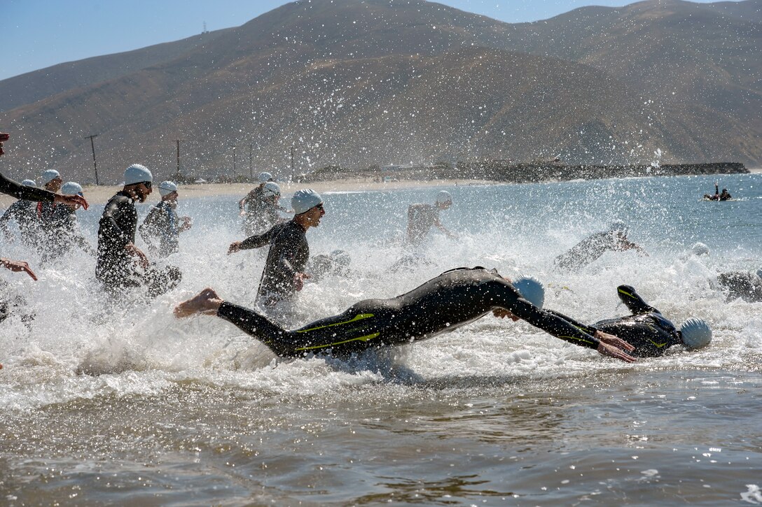 Swimmers run and dive in the ocean.